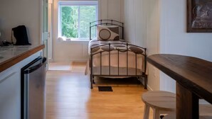 Une pièce de taille modeste comprenant un lit, une fenêtre, une table à manger et un coin cuisine.