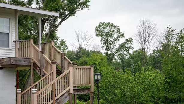 Un escalier en bois menant à un porche, un lampadaire et un bassin dans un jardin.