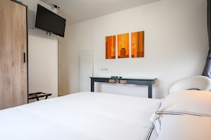 Una habitación de hotel con una cama, un escritorio, un televisor en la pared y una puerta.