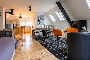 A modern loft apartment with a kitchen, dining area, and a large window. - Apartment 'Gîte À L'orée Du Verger' with Mountain View, Wi-Fi and Air Conditioning (Griesbach-au-Val)