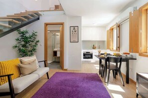 Ein modernes Apartment mit Treppe, Essbereich und Küche.