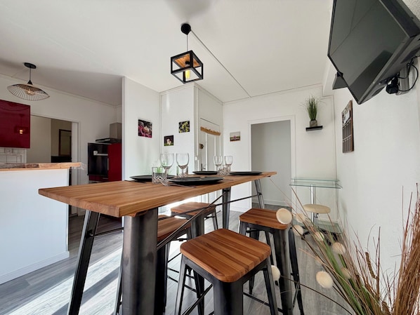 Une cuisine moderne avec une table en bois, des tabourets de bar et un luminaire suspendu.
