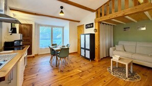 A spacious living area with wooden floors, a dining table, a sofa, and a kitchen with a stove and refrigerator.