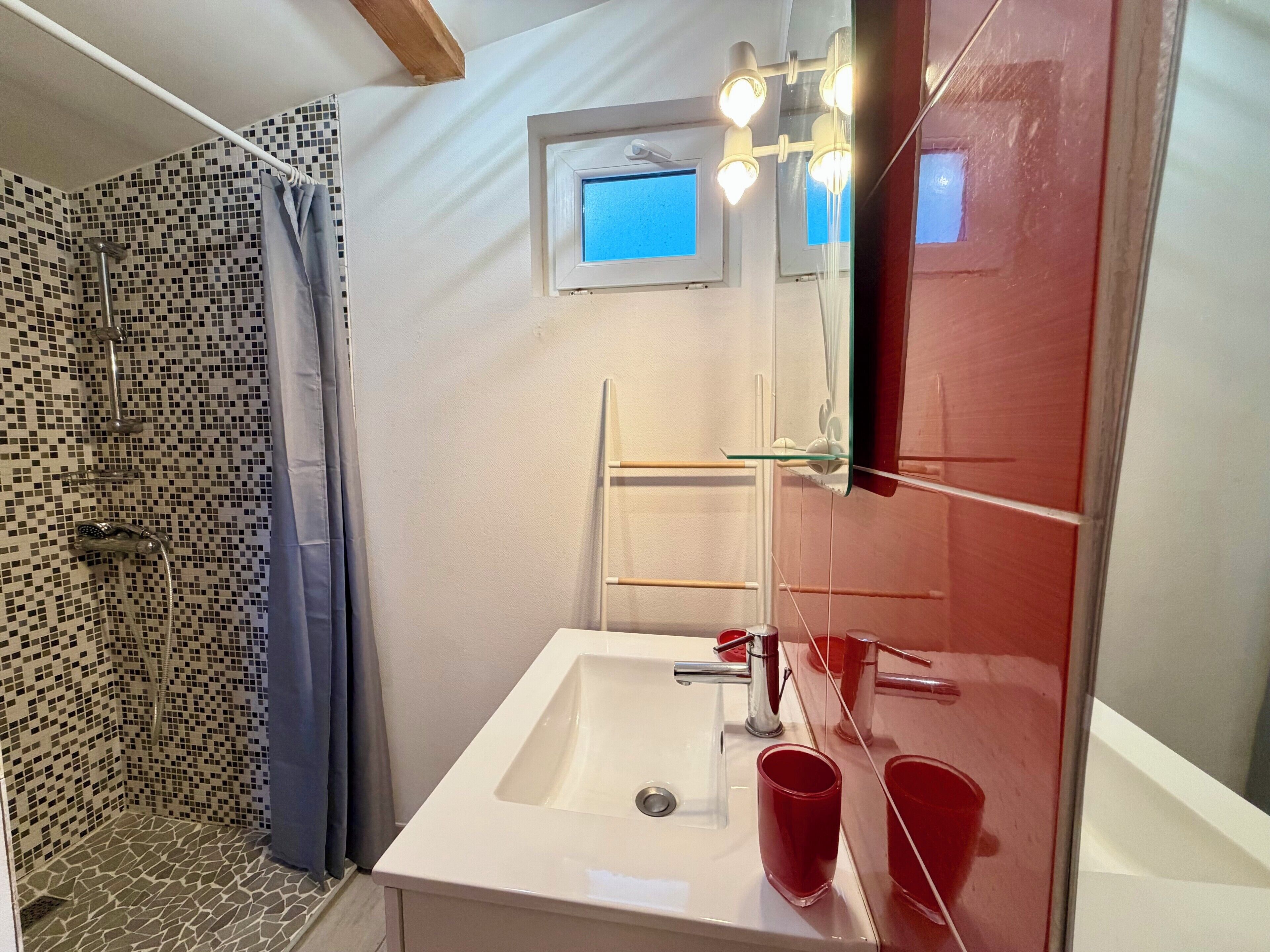 A bathroom with a shower, a sink, and a mirror.
