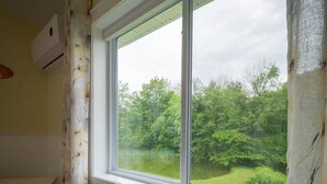 Une pièce dotée d’une grande fenêtre, d’un banc en bois, d’un radiateur et d’un climatiseur fixé au mur.