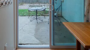 A room with a sliding glass door leading to an outdoor patio with a table and chairs.
