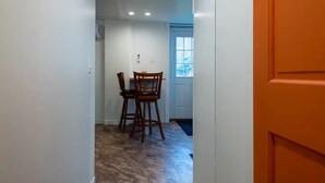 A hallway with a dining area at the end, featuring a table and chairs.