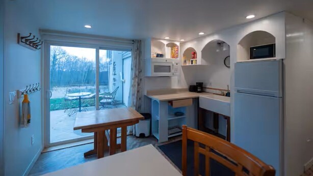 A compact kitchen with a dining area, a refrigerator, a microwave, and a small window.