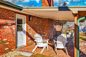 A brick house with a covered patio, outdoor seating, and a chimney.