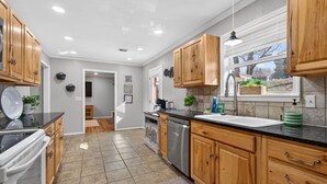 Una cucina moderna con mobili in legno, un piano di lavoro nero e una lavastoviglie in acciaio inossidabile.