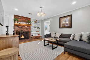 A living room with a fireplace, a sofa, a coffee table, and a bookshelf.