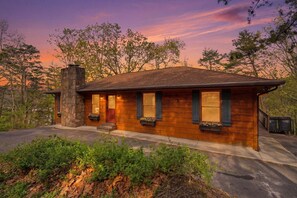 A single-story wooden house with a stone chimney, a front porch, and a driveway. - Relaxing Cabin: Views, Hot Tub, Theater, Games! (Pigeon Forge)