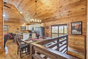 L’intérieur d’un chalet en bois comprend une cuisine, un coin repas et offre une vue sur l’extérieur.