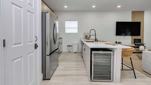 Una cuina moderna amb nevera integrada, una petita illa amb un rentaplat i un televisió de pantalla plana penjada a la paret.