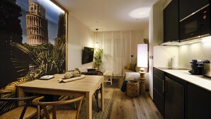 A modern kitchen with a dining area, a large window with a view of the Leaning Tower of Pisa, and a flat-screen TV mounted above the counter. - Premium Suite Toscana, non-smoking (Avilés)