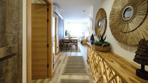 A hallway with a wooden door, a dining area with a table and chairs, and two large circular wall decorations. - Premium Suite Toscana, non-smoking (Avilés)