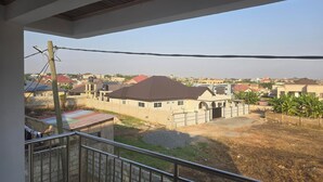 Ein Wohngebiet mit Häusern, blauem Himmel und einem Balkon mit Metallgeländer.