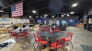 An indoor space with tables and chairs, a large American flag, and a sign reading 'RoCo Social.' - Furnished Rental near Oakridge in Historic Downtown Harriman (Harriman)