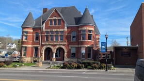 A historic brick building with a turreted roof, a prominent entrance with arches, and a sign indicating it is the Harriman Fire Station 1. - Furnished Rental near Oakridge in Historic Downtown Harriman (Harriman)