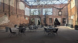 Ein Straßencafé mit Ziegelwänden, großen Fenstern und Metalltischen und -stühlen.