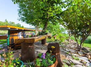 A rustic outdoor setting with a wooden bench, a stone pathway, and a small wooden structure. - Villa Roza Dalmatian Escape (Tucepi)