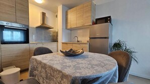 A modern kitchen with wooden cabinets, a built-in oven, a microwave, and a refrigerator. - Apartman Fitt (Zagreb)