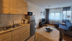 A compact kitchen with wooden cabinets, a built-in microwave, and a refrigerator. - Apartman Fitt (Zagreb)