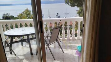 A balcony with a table and chairs, overlooking a body of water with boats.