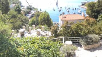 A coastal town with boats, greenery, and a building with a tiled roof.