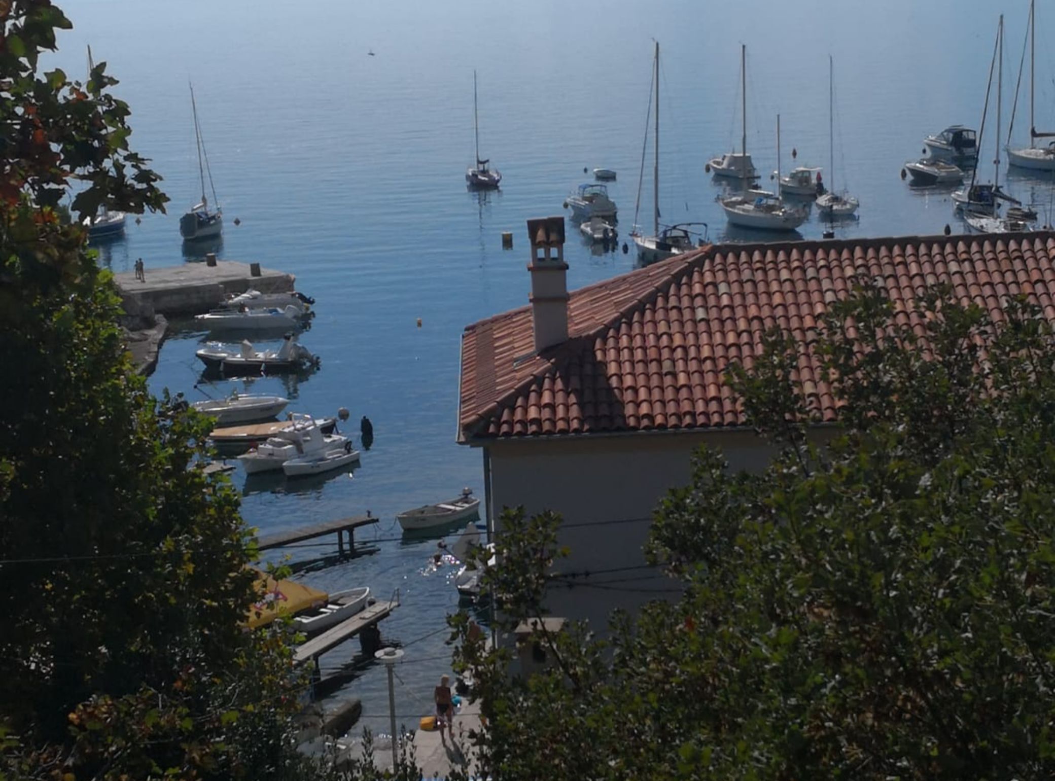 Ein Yachthafen mit vertäuten Booten, ein Gebäude mit Ziegeldach und freier Wasserblick.