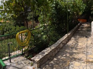 A stone pathway bordered by a stone wall, a green metal fence, and lush greenery. - Comfort Kostrena Apartments Rijeka (Kostrena)