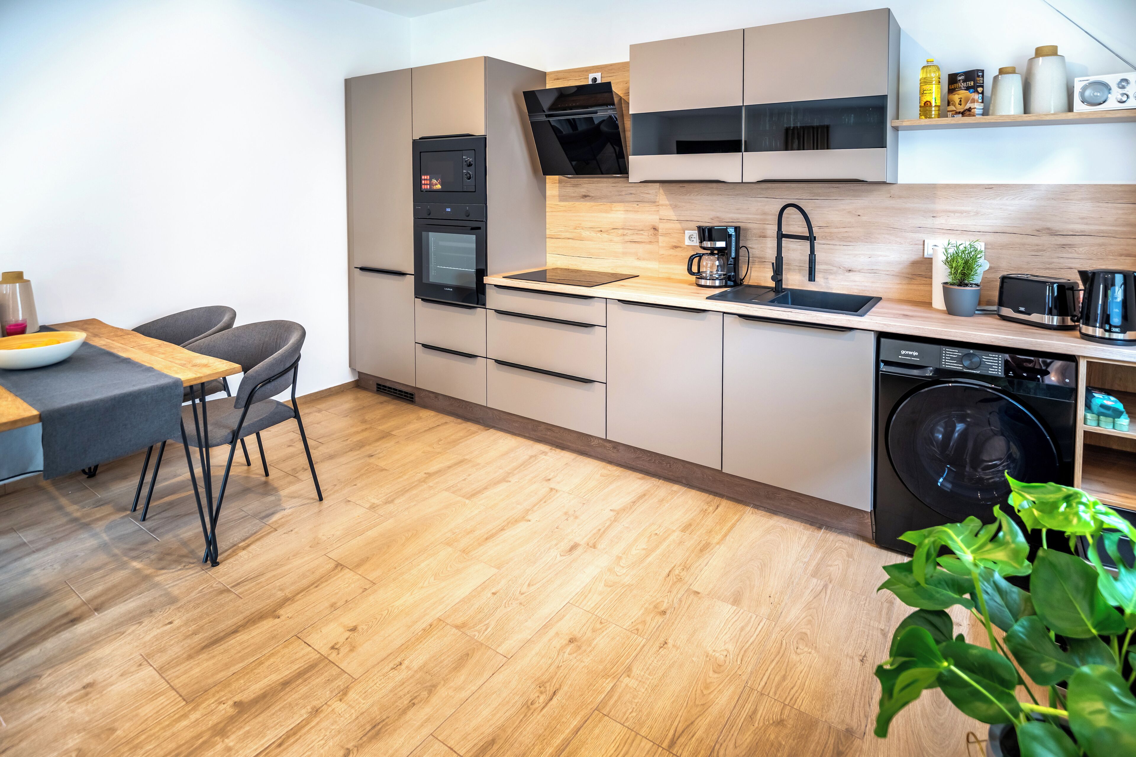 Eine moderne Küche mit Backofen, Mikrowelle, Kaffeemaschine und Geschirrspüler.