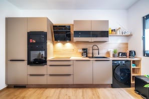 A modern kitchen with built-in appliances, a coffee machine, and a washing machine.