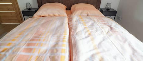A double bed with a checkered bedspread, two bedside tables, and a wooden wardrobe.