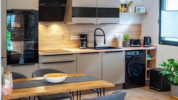 Eine moderne Küche mit Backofen, Kaffeemaschine, Spüle und Waschmaschine.