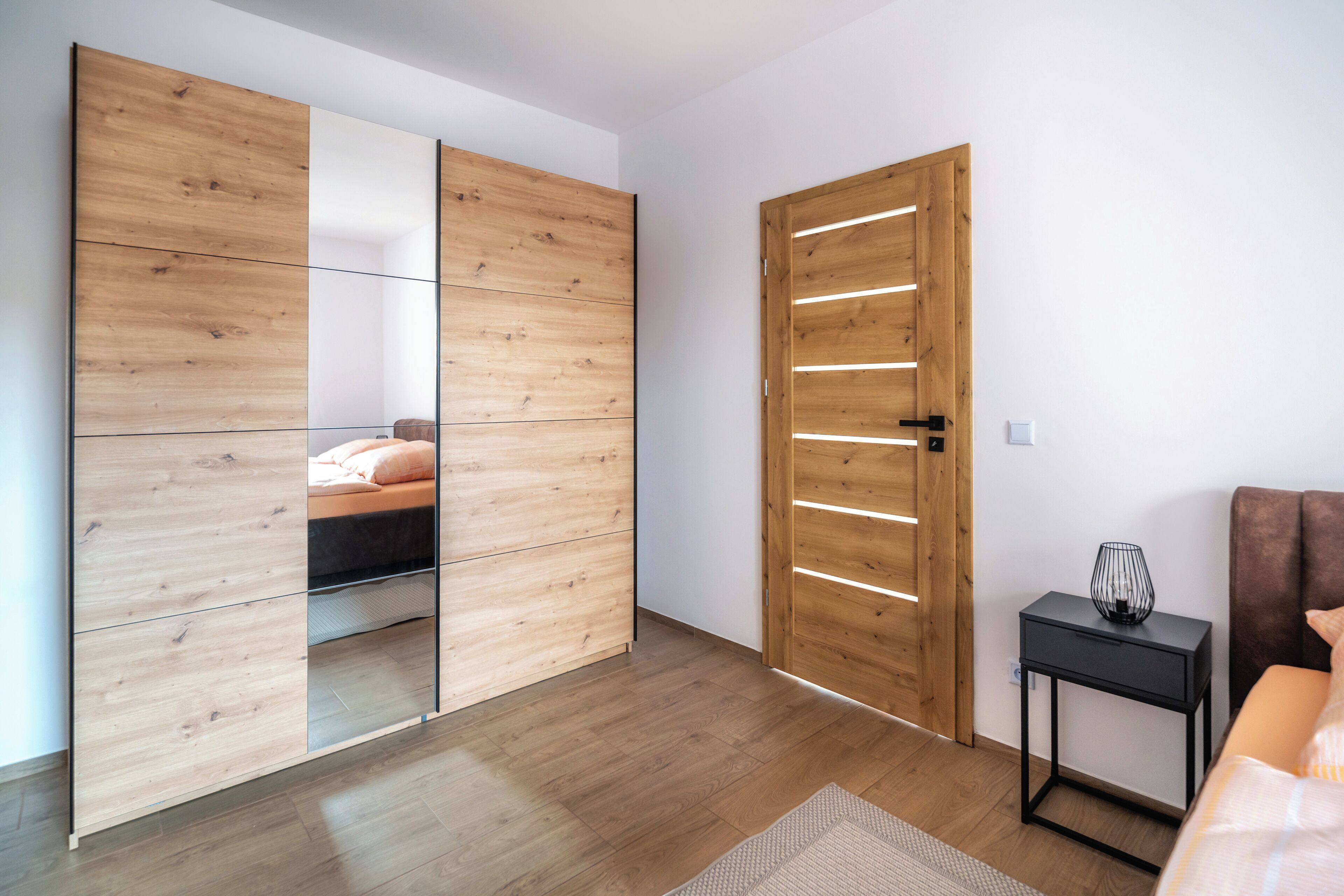 Ein modernes Schlafzimmer mit einem Holzschrank, einem Nachttisch und einem Bett mit Kopfteil.