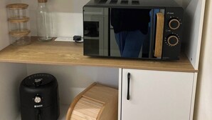 A kitchen with white cabinets, a microwave, a coffee maker, and a wooden bread box. - Wimbleball Lake View Cabin Sleeps up to 3 (Dulverton)