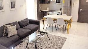 A modern living room with a sofa, a glass coffee table, and a patterned rug. - Embassy Gardens Exquisite (Accra)