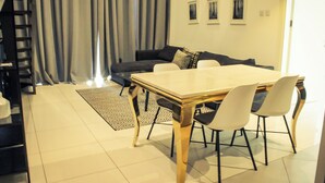 A modern living room with a dining table, chairs, a sofa, and a patterned rug. - Embassy Gardens Exquisite (Accra)