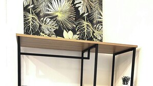 Une étagère en bois à plusieurs niveaux, dotée d’une structure en métal noir, et contenant des paniers en osier et une petite plante en pot.