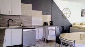 A modern kitchen with a dishwasher, a coffee maker, and a dining area with a table and chairs. - La Ferme de Liévin, jardin, wifi, 6pers (Liévin)