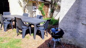 An outdoor patio with a table and chairs, a grill, and a stone wall. - La Ferme de Liévin, jardin, wifi, 6pers (Liévin)