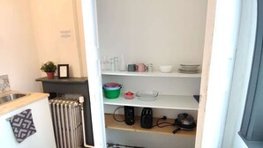 Eine Küche mit Heizkörper, Spüle und Regalen mit Küchenutensilien.