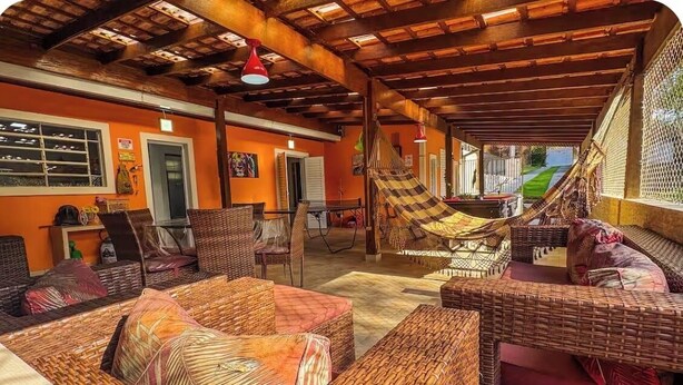 A covered outdoor seating area with wicker furniture and a hammock.