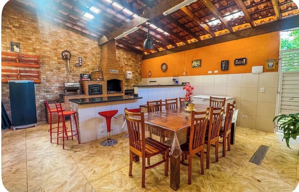 A kitchen with a brick wall, wooden ceiling, and a bar area with stools.