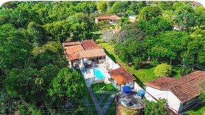 A residential property with a swimming pool, multiple buildings, and lush greenery.