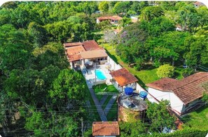 A residential property with a swimming pool, multiple buildings, and lush greenery.