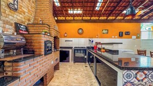 A kitchen with a brick oven, a coffee machine, and a tiled backsplash.