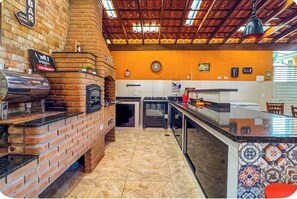 A kitchen with a brick oven, a coffee machine, and a tiled backsplash.