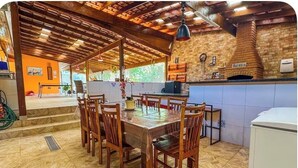 A dining area with a wooden table and chairs, a brick wall, and a hanging light fixture.